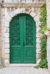 brick archway with green wooden door, creeper at the right side, mediterranean architecture