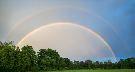 Fototapeta na wymiar double rainbow over green trees