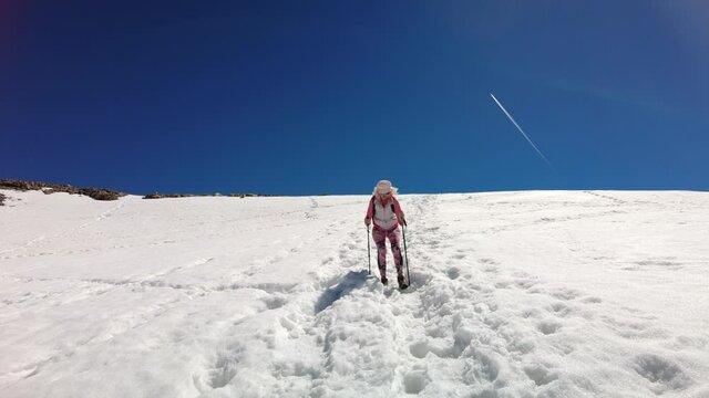 backside of backpacker girl with trekking poles walking on top of Diavolezza col between Munt Pers and Piz Trovat of Switzerland.