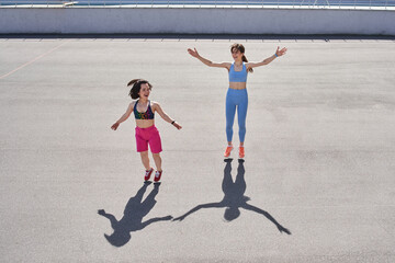 Two diverse girls jumping at the track at the stadium while having their morning workout
