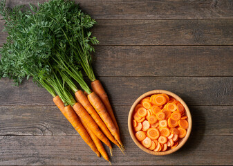 chopped carrots in a wooden bowl on a table, top view.