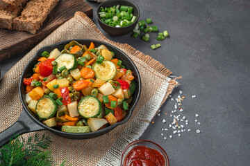 Healthy, baked vegetables and fresh herbs on a gray-brown background.