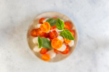 Delicious Italian Caprese salad with sliced red and orange cherry tomatoes.