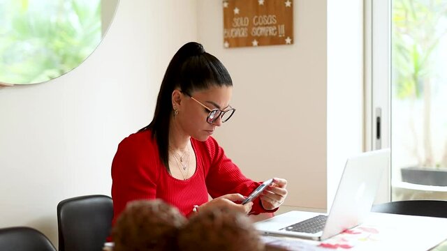 mujer latina senatada en la mesa de su hogar, haciendo negocios desde su laptop