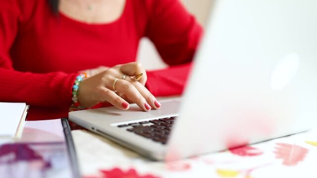 mujer latina senatada en la mesa de su hogar, haciendo negocios desde su laptop