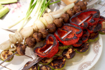 Grilled vegetables. Bulgarian pepper, mushroom mushrooms mushrooms on skewers. Green onions on a white table. Vegan kebab