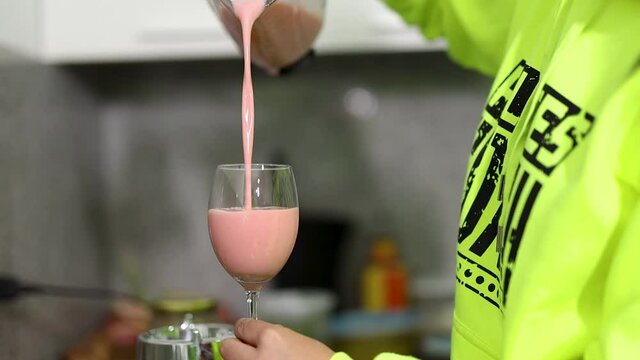 mujer se sirve un refrescante jugo de fresa en una copa de vidrio
