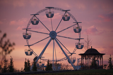 Big white Ferris wheel in a foggy park at dawn.
