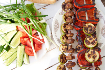 Grilled vegetables. Bulgarian pepper, mushroom mushrooms mushrooms on skewers. Green onions on a white table. Vegan kebab