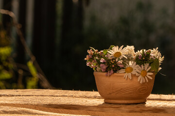 a bouquet of wild flowers in the rays of the sun. the bouquet stands on a wooden table. drops of dew on a flower