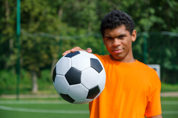 Closeup soccer ball in hand of young African American man on sports court
