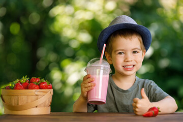 little boy holding disposable plastic glass of strawberry milkshake
