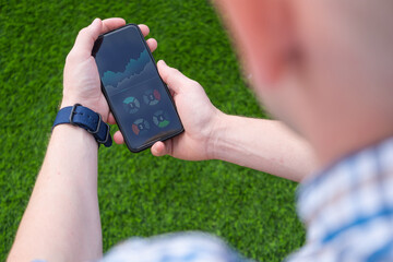 Concept of Young money,  trading platforms, investing. Smartphone with open charts, stock tickers or graphs in man's hand.
