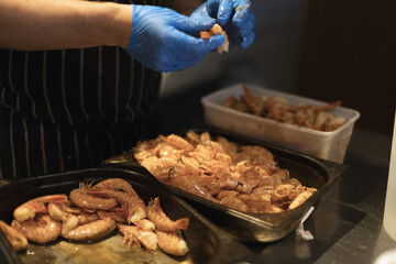 chef peeling shrimp with blue gloves
