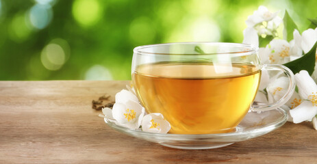 Cup of jasmine tea and fresh flowers on wooden table outdoors, space for text. Banner design