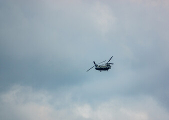 Fototapeta na wymiar RAF Boeing Chinook UH-1 helicopter flying low in a cloudy blue grey and white summer sky