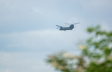 RAF Chinook tandem-rotor CH-47 helicopter flying fast and low in a cloudy blue white sky on a military battle exercise, Wilts UK
