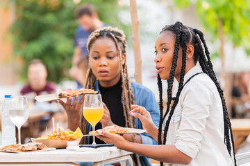 Talking afro american women holding delicious pizza slices: Selective focus