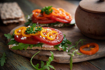 Sandwich with tomatoes, paprika and arugula on a wooden table