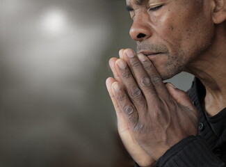 man praying to god with hands together Caribbean man praying with people stock image stock photo