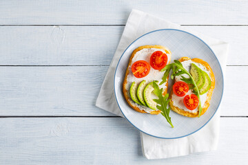 Avocado toasts with cream cheese and cherry tomatoes. Two toasts with avocado and arugula on white boards. Copy space. Top view