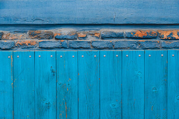Vintage wood background with peeling paint and row of dilapidated bricks. Old wall textures closeup. Shabby wooden planks with knots and nailheads