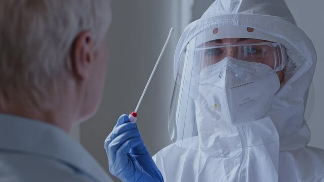 Medical worker doctor nurse woman wearing personal protective equipment respirator mask doing coronavirus swab on female old patient, Covid-19 pcr test for sick contagious elderly unrecognizable lady