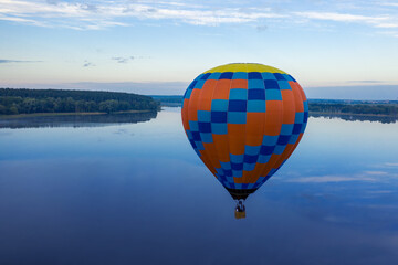 Yellow-blue balloon over the lake on a background of dawn.