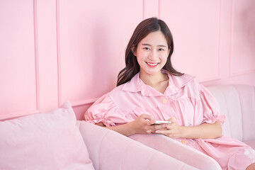 Happy Asian businesswoman using mobile phone at pink room