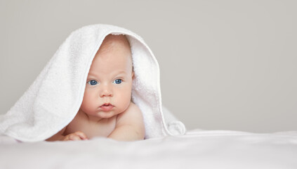 Close-up portrait of cute baby boy in white terry towel on white background. Bathing babies and restful sleep. funny   child face..