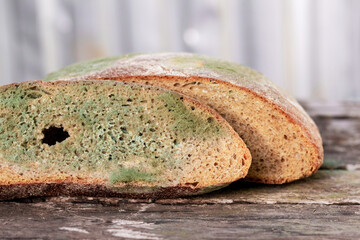 A slice of bread covered with mold on a wooden surface