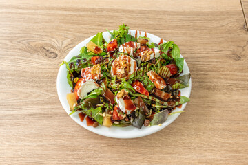 Goat roll salad with pieces of quince, sunflower seeds, chopped walnuts, raisins and tender shoots of lettuce and spinach drizzled with oil and balsamic vinegar.