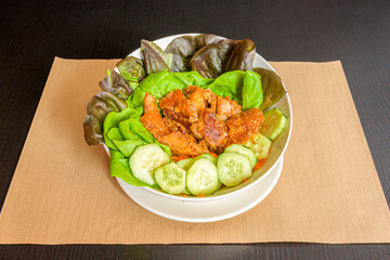 Mixed lettuce salad, fried pork rinds, grated carrots and sliced cucumbers