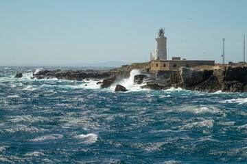 Waters of the Mediterranean sea whipping the breakwater of the Tarifa lighthouse in southern Spain
