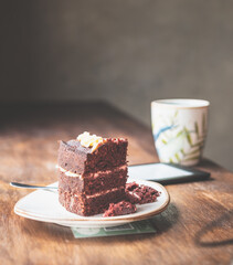 A table with a cup of coffee, a cake, and an e-reader