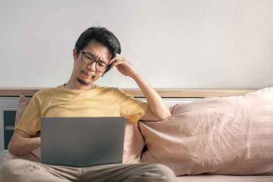 Asian man have work with laptop on bed in bedroom, Work from home, online work, education, boring.