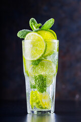Mojito cocktail on a dark background. Refreshing drink with lime, mint and ice. Summer cocktail close-up