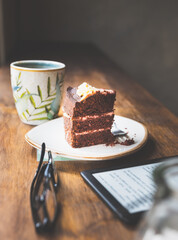 A table with a cup of coffee, a cake and a glasses