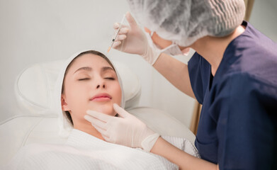 Fototapeta na wymiar Beauty clinic concept. Asian woman lying on bed and cosmetologist does injections to face augmentation for anti wrinkle in beauty clinic.