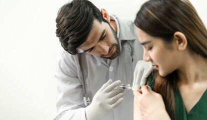 Male doctor with syringe doing injection of vaccine to female patient.