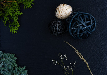 Decorative Christmas composition with ornament balls, fir tree and dried plant on black textured background