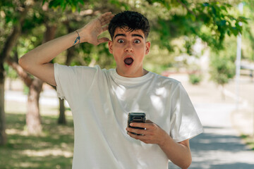 teenager boy with mobile phone and expression of surprise and amazement on the street