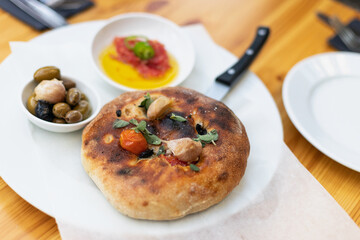 Italian focaccia with cherry tomatoes, thassos olives, oregano, olive oil and sea salt. served with salsa and olives