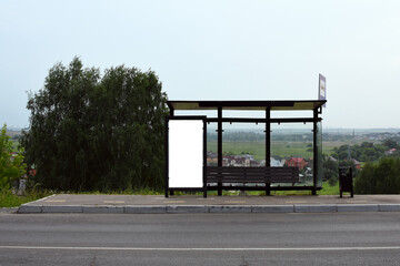 Vertical white billboard at a bus stop on a street. background with buildings and road. Make fun of. A poster on the street next to the roadway. Summer day. Empty stop.Waiting place for bus
