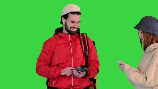 Delivery man holding payment terminal, young girl paying for delivery on a Green Screen, Chroma Key.