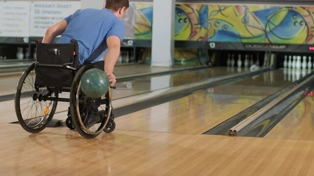 Two young disabled men in wheelchairs playing bowling in the club