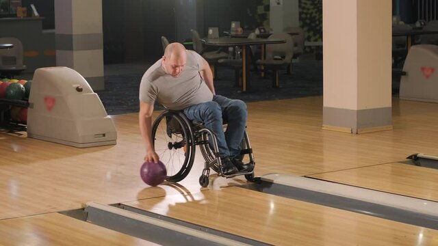 Two young disabled men in wheelchairs playing bowling in the club
