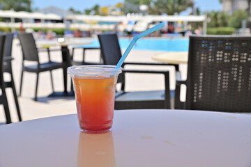 Alcoholic cocktail in a transparent plastic cup with a straw