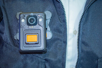 Chest video recorder hangs on jacket. Chest DVR close-up. Small DVR is attached to jacket....