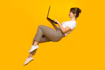 Freelancer woman with laptop. Freelance girl lies in zero gravity. Freelancer with a computer in an unusual pose. Freelancer works with a laptop. Creative portrait of a girl with a computer.